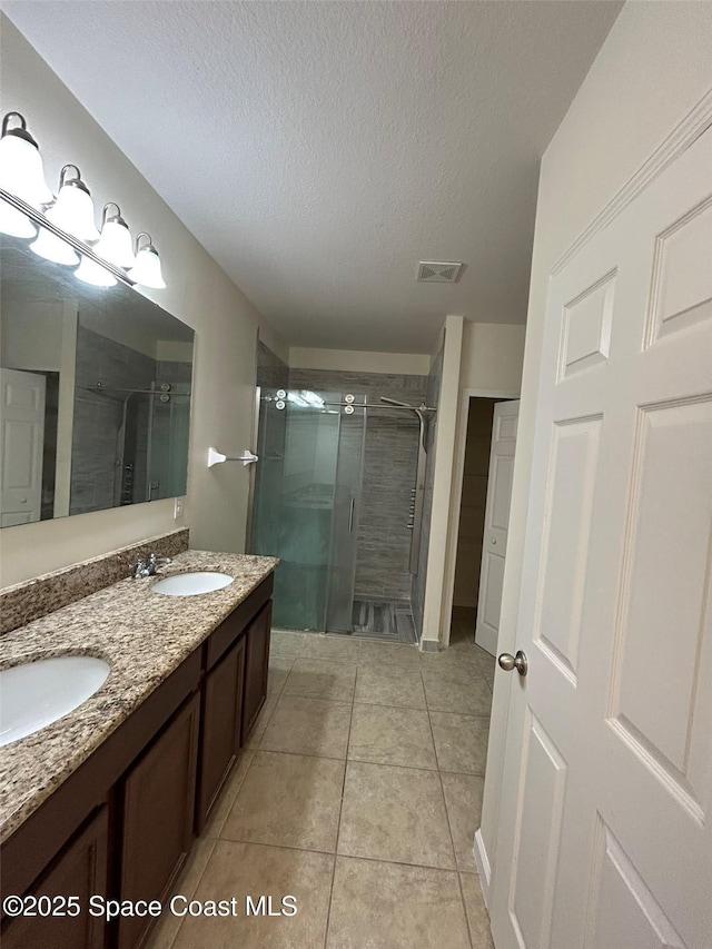 bathroom featuring tile patterned floors, a shower with shower door, a textured ceiling, and vanity