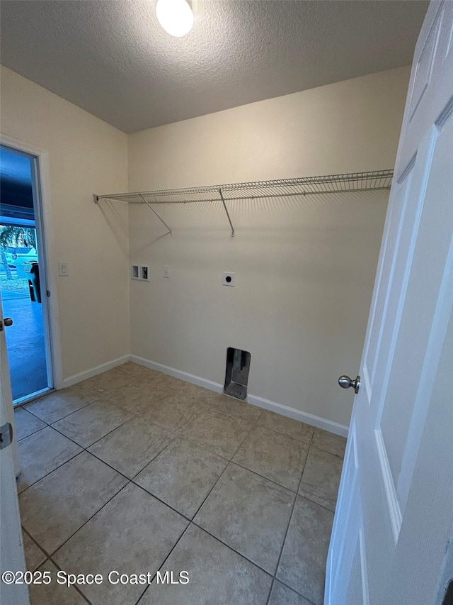 clothes washing area with electric dryer hookup, hookup for a washing machine, a textured ceiling, and light tile patterned floors