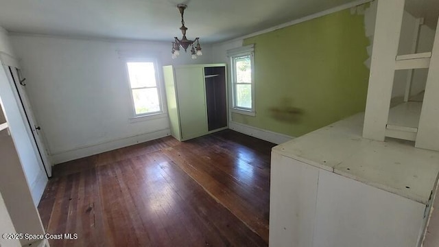 empty room with dark wood-type flooring and a chandelier