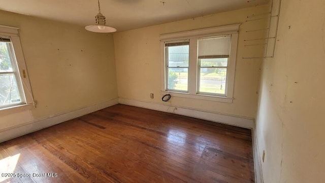 empty room with a healthy amount of sunlight and dark hardwood / wood-style flooring