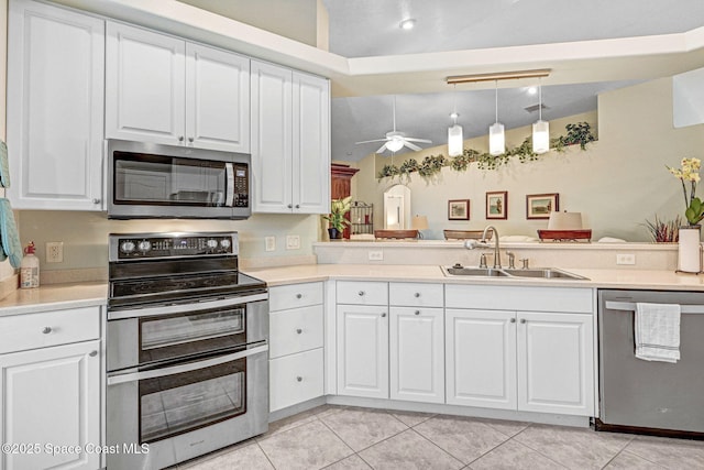 kitchen featuring stainless steel appliances, white cabinetry, sink, and pendant lighting