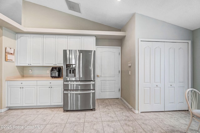 kitchen featuring white cabinetry, vaulted ceiling, light tile patterned floors, and stainless steel fridge with ice dispenser