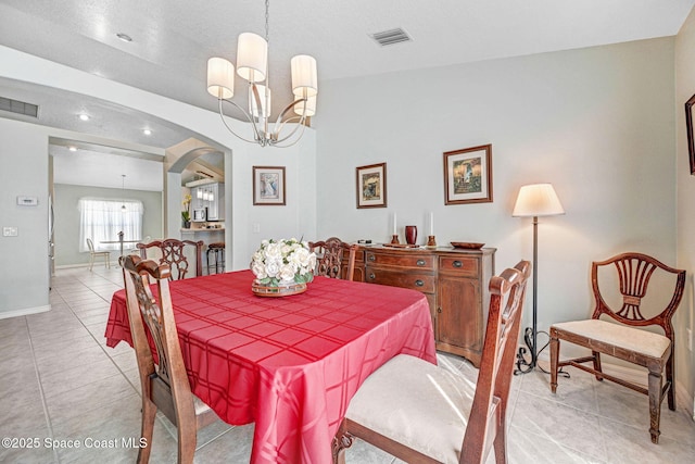 dining space with light tile patterned floors and an inviting chandelier