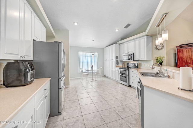 kitchen with sink, stainless steel appliances, white cabinets, light tile patterned flooring, and decorative light fixtures