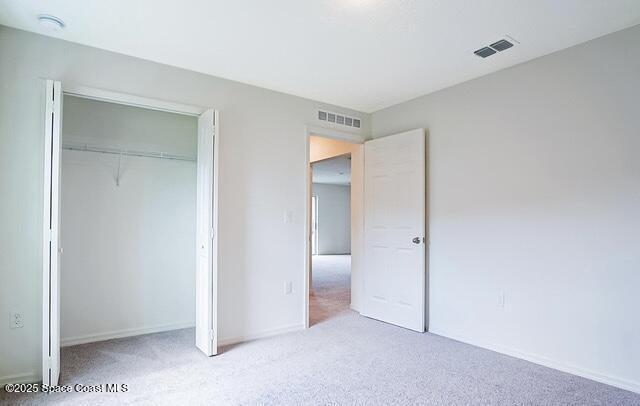 unfurnished bedroom featuring light colored carpet and a closet