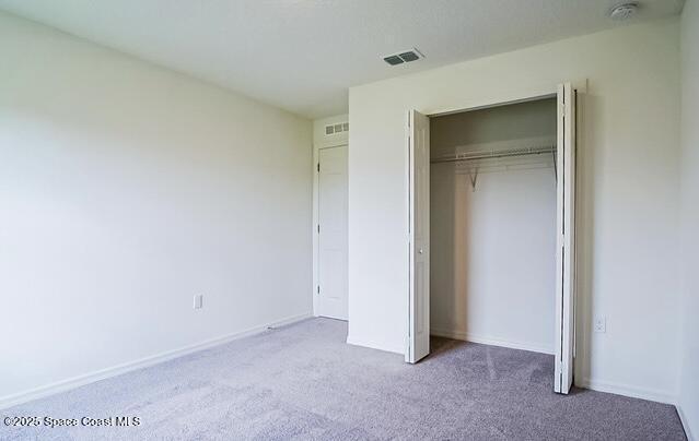 unfurnished bedroom with light carpet and a closet