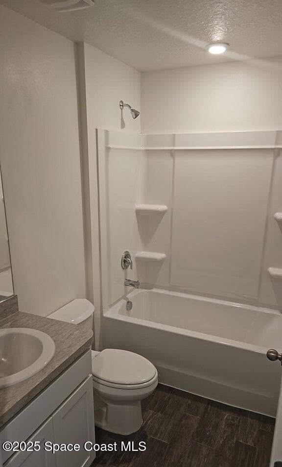 full bathroom featuring vanity, bathtub / shower combination, a textured ceiling, and toilet