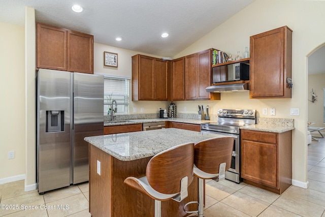 kitchen with appliances with stainless steel finishes, a breakfast bar, sink, a center island, and light stone counters