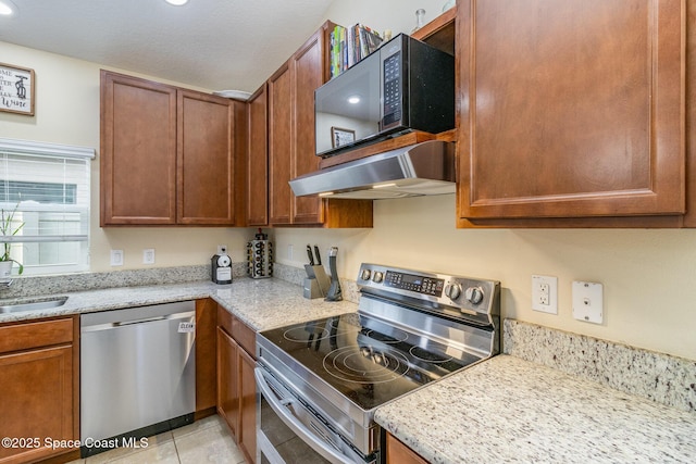 kitchen with light stone countertops, stainless steel appliances, sink, and light tile patterned flooring