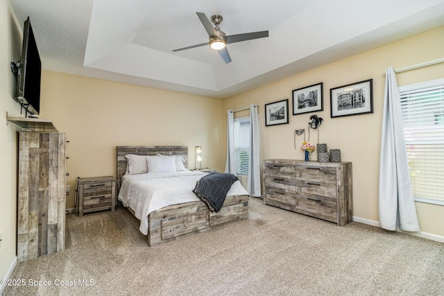 carpeted bedroom with ceiling fan, a tray ceiling, and a textured ceiling