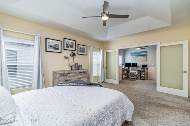 bedroom with lofted ceiling, ceiling fan, carpet flooring, a raised ceiling, and french doors