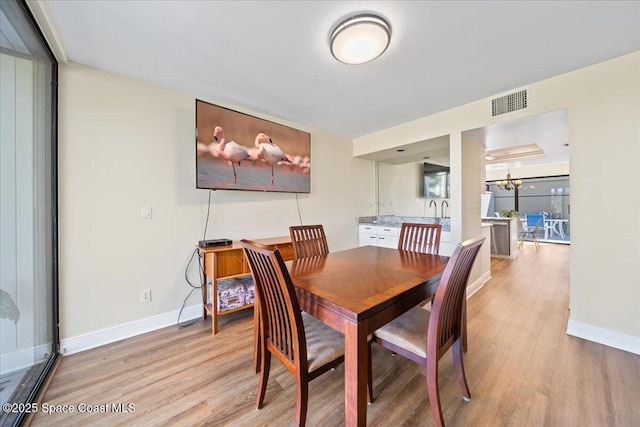 dining space with expansive windows, a notable chandelier, and light hardwood / wood-style flooring