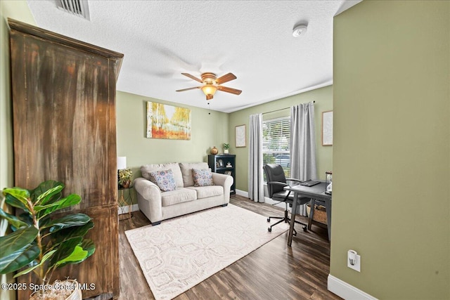 home office with dark wood-type flooring, ceiling fan, and a textured ceiling