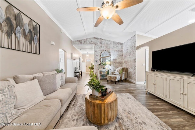 living room with ceiling fan, wood-type flooring, ornamental molding, brick wall, and vaulted ceiling