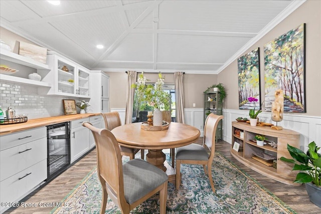 dining room with hardwood / wood-style floors, vaulted ceiling, ornamental molding, and beverage cooler