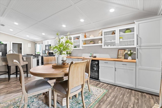 dining space featuring wood-type flooring, lofted ceiling, and beverage cooler