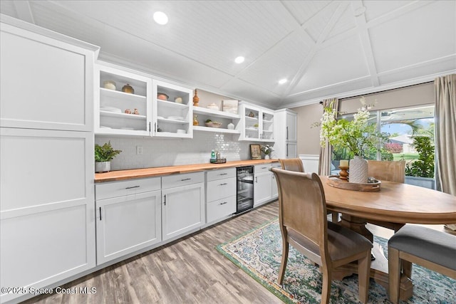 kitchen featuring white cabinetry, wooden counters, vaulted ceiling, beverage cooler, and light hardwood / wood-style floors