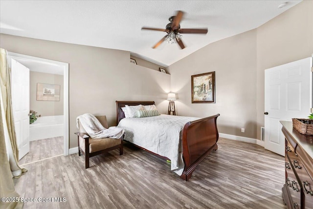 bedroom featuring vaulted ceiling, ensuite bathroom, hardwood / wood-style floors, ceiling fan, and a textured ceiling