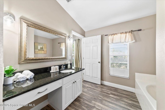 bathroom featuring vanity, a bath, hardwood / wood-style flooring, and vaulted ceiling