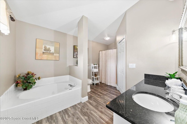 bathroom with toilet, vaulted ceiling, vanity, a bathtub, and hardwood / wood-style floors