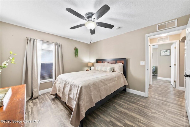 bedroom featuring ceiling fan, dark hardwood / wood-style floors, and a textured ceiling