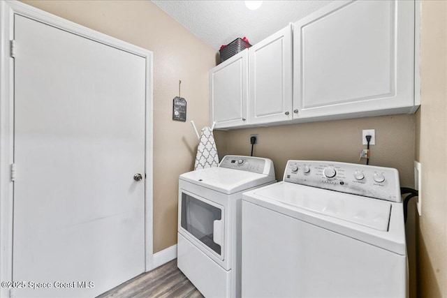 washroom with a textured ceiling, light hardwood / wood-style flooring, cabinets, and washing machine and clothes dryer