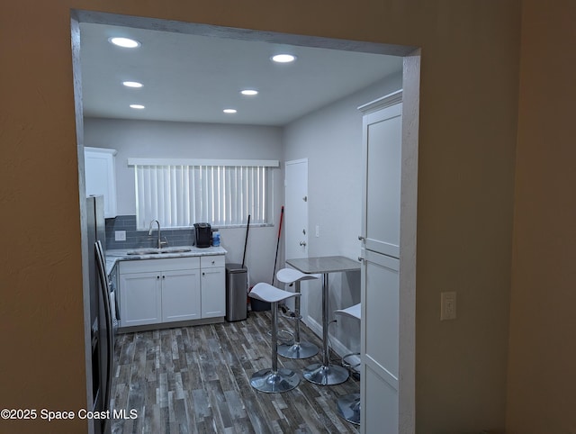 kitchen with sink, white cabinetry, fridge, dark hardwood / wood-style floors, and decorative backsplash