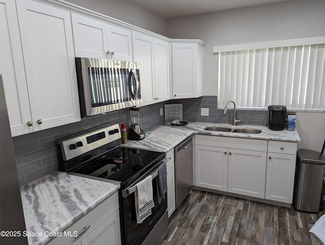 kitchen with stainless steel appliances, white cabinetry, sink, and light stone counters