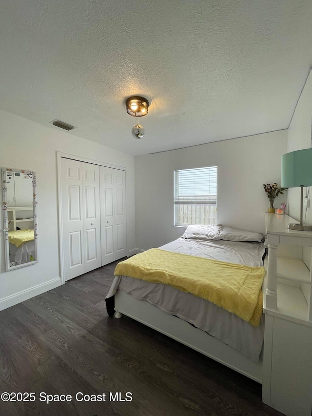 bedroom featuring a textured ceiling, dark hardwood / wood-style flooring, and a closet