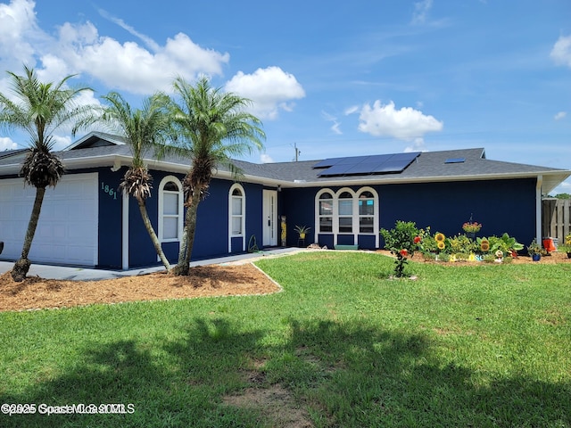 view of front of property with a garage, a front yard, and solar panels