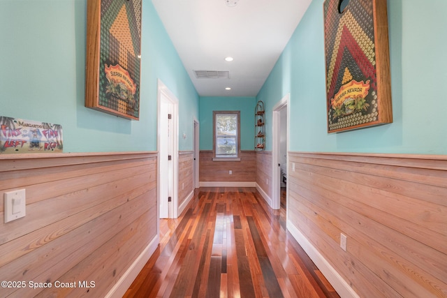 corridor with hardwood / wood-style flooring and wood walls