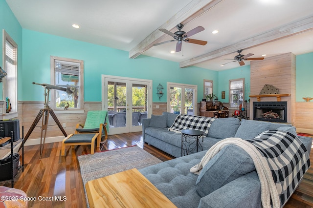 living room with french doors, a large fireplace, dark hardwood / wood-style floors, wooden walls, and beamed ceiling