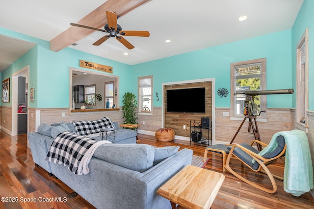 living room featuring wooden walls, ceiling fan, beam ceiling, and hardwood / wood-style floors