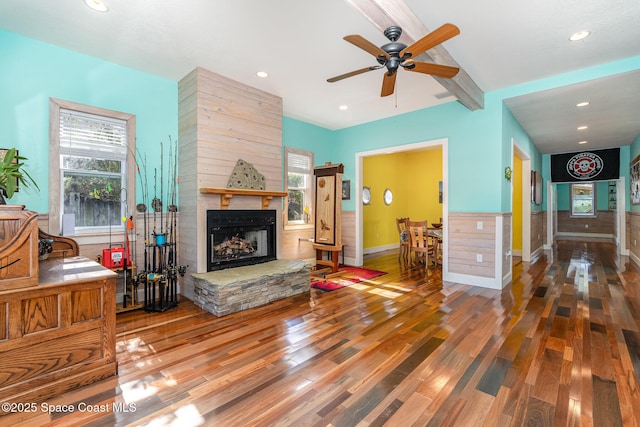 living room with beamed ceiling, a healthy amount of sunlight, a fireplace, and hardwood / wood-style floors