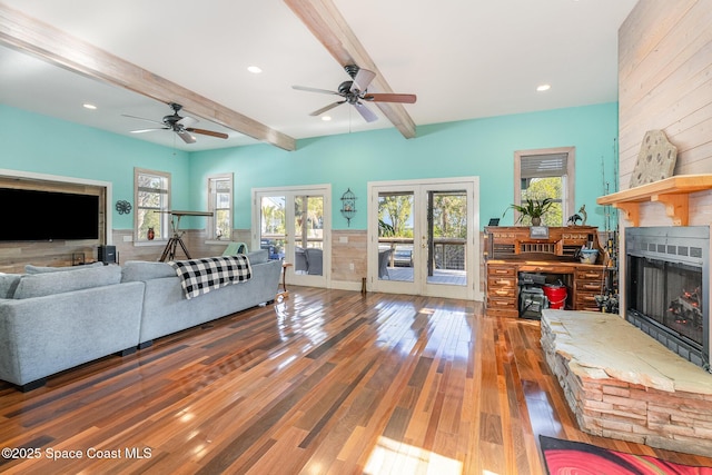 living room featuring french doors, beam ceiling, dark hardwood / wood-style floors, ceiling fan, and a fireplace