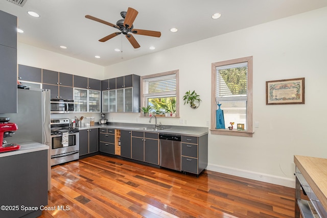 kitchen with stainless steel appliances, sink, dark wood-type flooring, and gray cabinetry