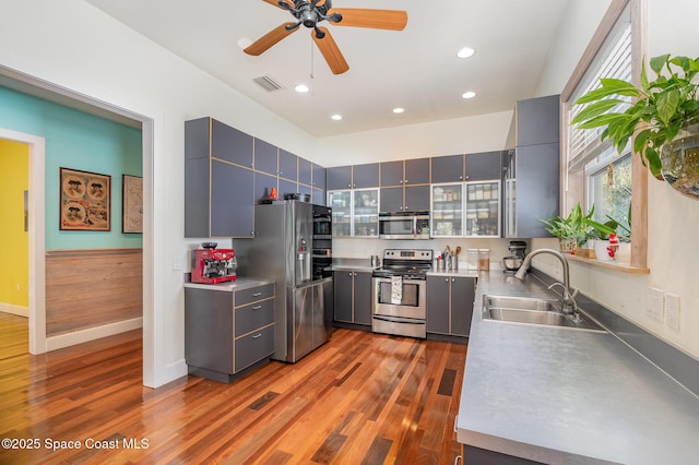 kitchen with sink, gray cabinetry, appliances with stainless steel finishes, dark hardwood / wood-style floors, and ceiling fan