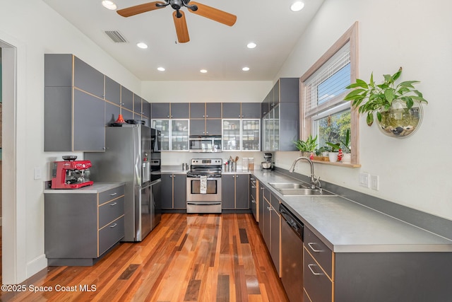 kitchen with stainless steel appliances, sink, light hardwood / wood-style floors, and gray cabinets