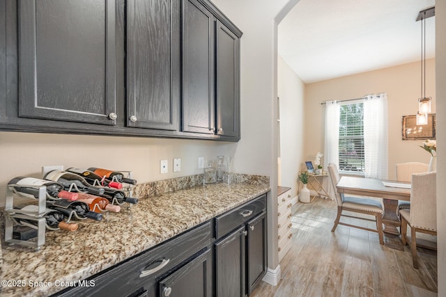 kitchen with pendant lighting, light stone countertops, and light wood-type flooring