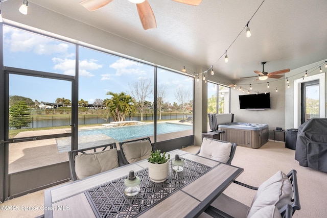 sunroom featuring ceiling fan and a water view