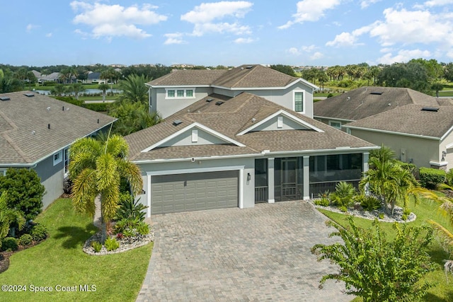 view of front of home featuring a garage, a front lawn, and a sunroom