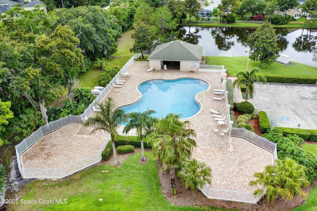 view of pool with a water view, a patio, and a lawn