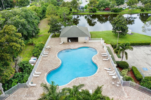 view of pool featuring a water view, a patio, and a lawn