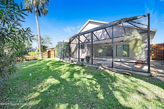 rear view of house featuring a lawn and glass enclosure