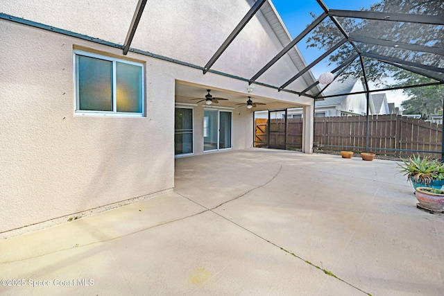 view of patio featuring ceiling fan and glass enclosure