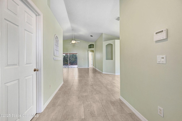 hall featuring lofted ceiling, a textured ceiling, and light tile patterned flooring