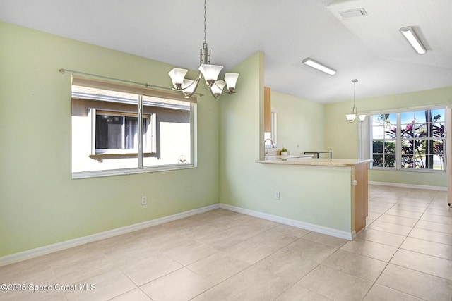 spare room featuring lofted ceiling, light tile patterned floors, and an inviting chandelier