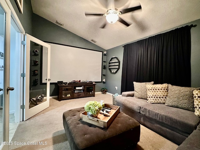 home theater room featuring ceiling fan, a textured ceiling, light carpet, vaulted ceiling, and french doors