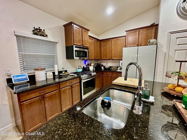 kitchen featuring sink, dark stone counters, and appliances with stainless steel finishes