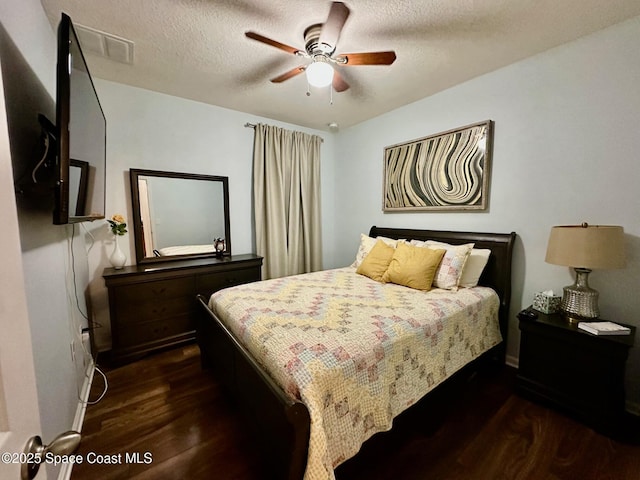 bedroom featuring ceiling fan, dark hardwood / wood-style flooring, and a textured ceiling